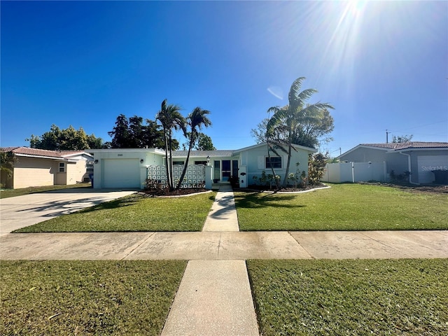 view of front of house featuring driveway, a front lawn, an attached garage, and fence