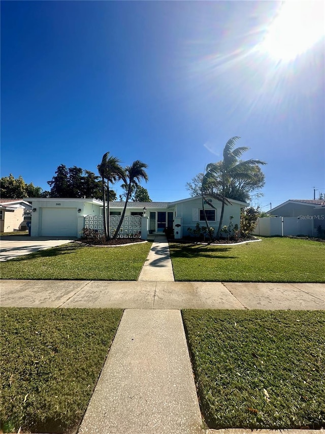 view of front of home featuring concrete driveway, a front lawn, an attached garage, and fence