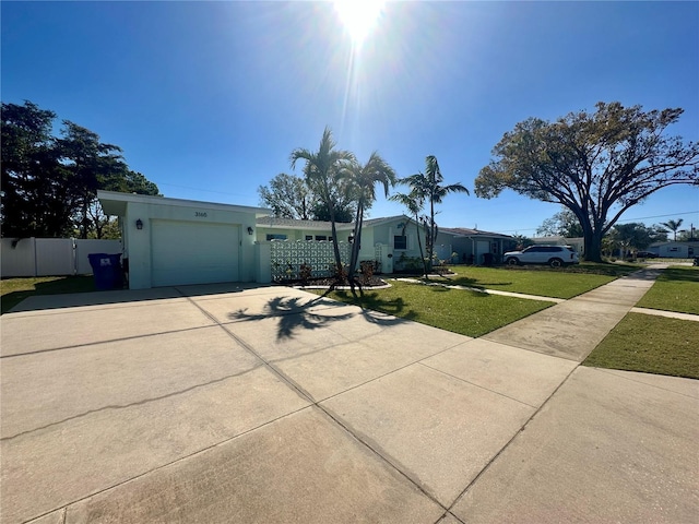 view of front of house featuring an attached garage, fence, a front lawn, and concrete driveway