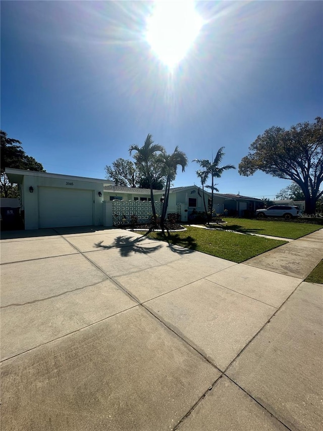 view of front of property featuring concrete driveway, a front lawn, and an attached garage