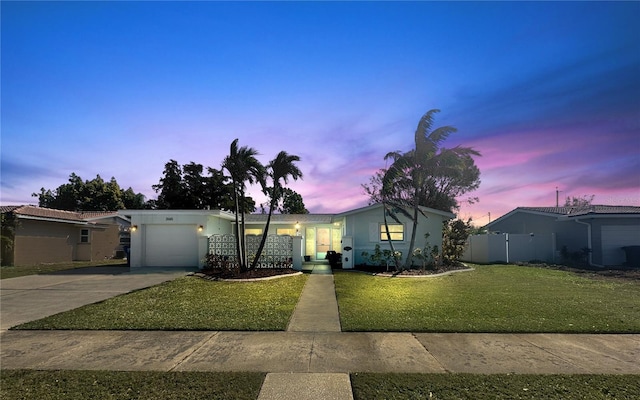 view of front of house featuring concrete driveway, an attached garage, a front lawn, and fence