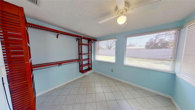 spare room with baseboards, visible vents, a ceiling fan, a textured ceiling, and light tile patterned flooring