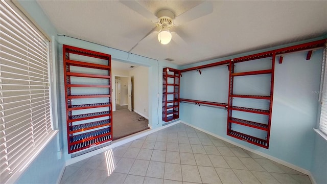 interior space with ceiling fan, baseboards, and light tile patterned floors