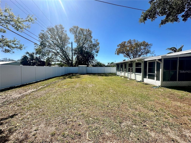 view of yard featuring a sunroom and a fenced backyard