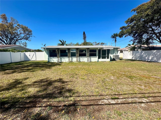 rear view of house featuring a sunroom, a fenced backyard, a gate, and a yard