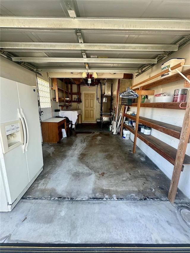 garage featuring heating unit and white fridge with ice dispenser