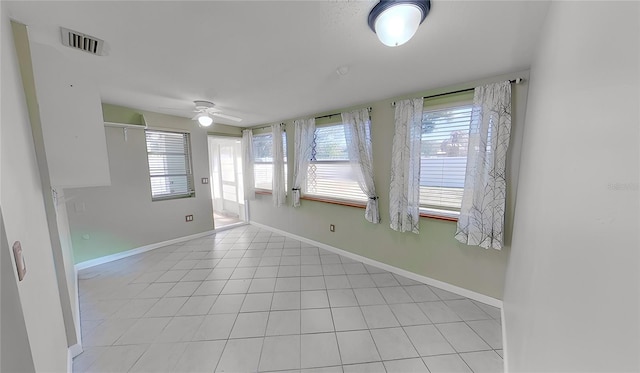 spare room with light tile patterned floors, ceiling fan, visible vents, and baseboards