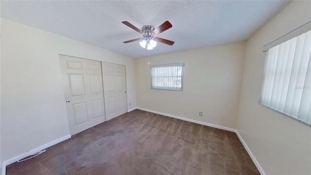 unfurnished bedroom featuring a textured ceiling, a closet, carpet flooring, and baseboards