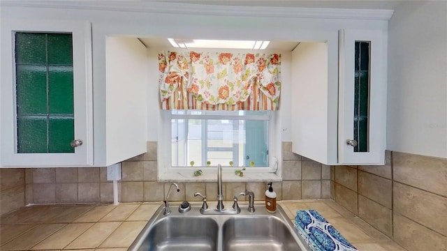 kitchen featuring ornamental molding, light countertops, white cabinetry, and a sink