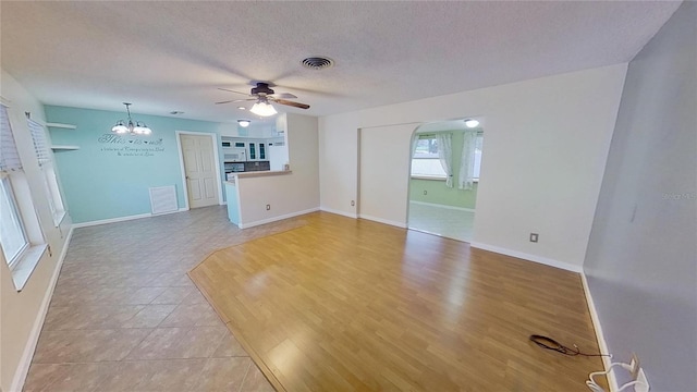 unfurnished living room with a textured ceiling, visible vents, and baseboards