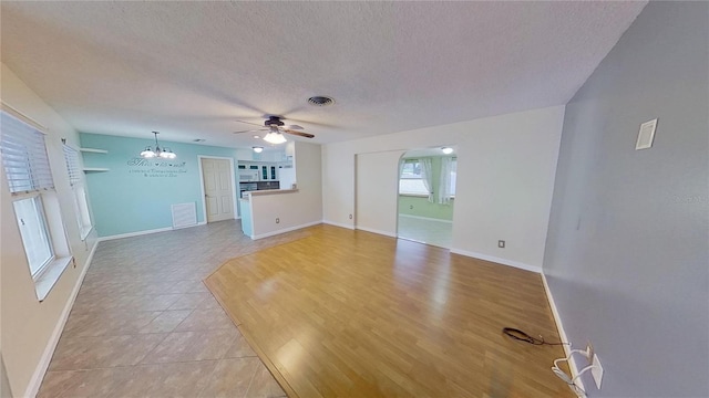 spare room with a textured ceiling, visible vents, and baseboards