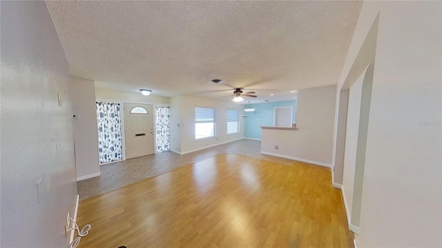 unfurnished living room featuring light wood-style floors, baseboards, and a textured ceiling