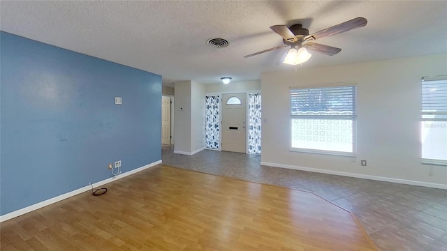 interior space with baseboards, visible vents, a textured ceiling, and wood finished floors