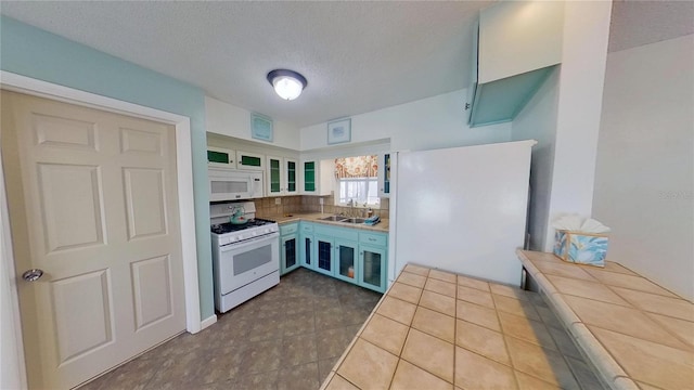 kitchen featuring glass insert cabinets, white appliances, a sink, and a textured ceiling