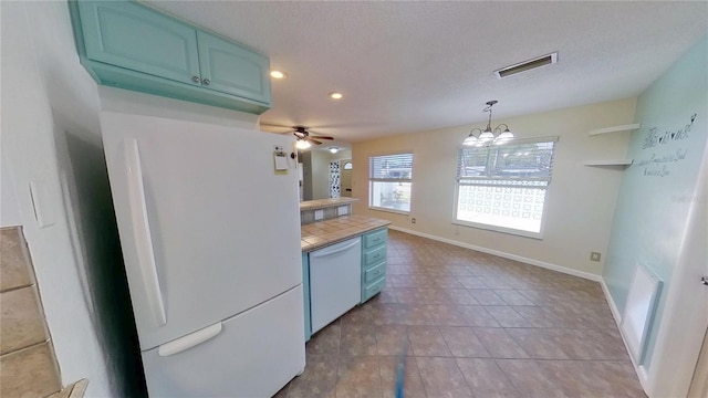 kitchen featuring baseboards, white appliances, visible vents, and blue cabinets