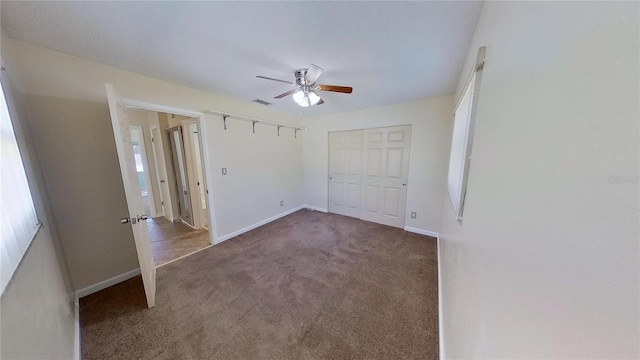 unfurnished bedroom featuring baseboards, visible vents, a ceiling fan, carpet floors, and a closet