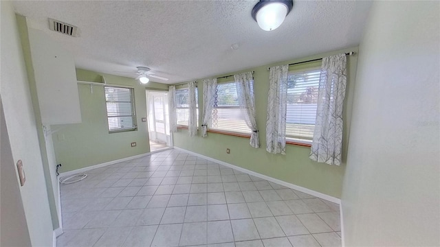 empty room with a textured ceiling, plenty of natural light, visible vents, and baseboards