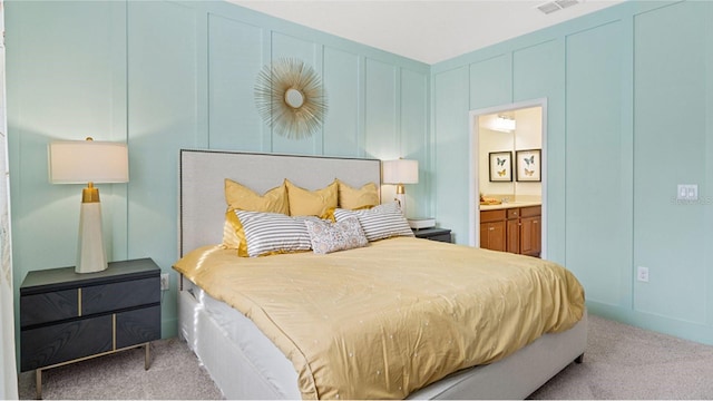 carpeted bedroom featuring ensuite bathroom, visible vents, and a decorative wall