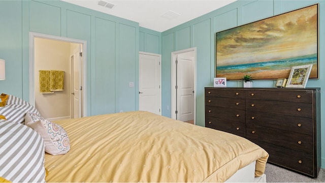 bedroom featuring carpet flooring, visible vents, and a decorative wall