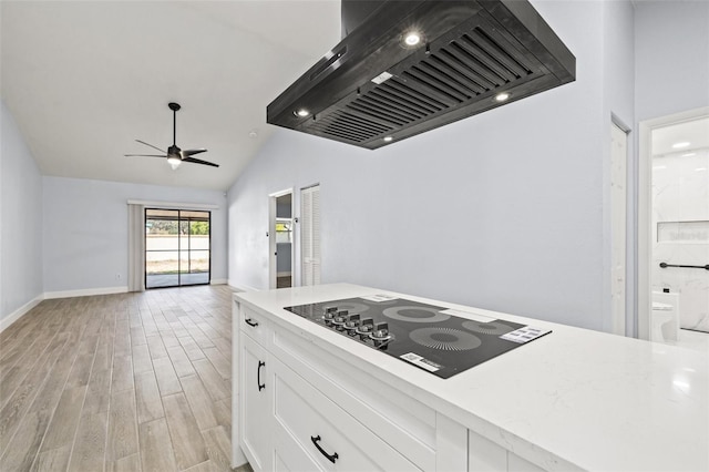 kitchen featuring premium range hood, light wood finished floors, light countertops, white cabinetry, and black electric cooktop