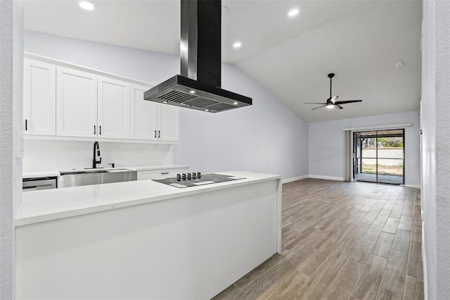 kitchen with light wood finished floors, black electric stovetop, exhaust hood, white cabinets, and a sink