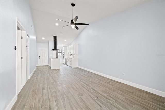 unfurnished living room featuring light wood-style flooring, a ceiling fan, and baseboards