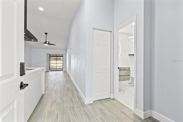 corridor featuring high vaulted ceiling, baseboards, and wood finish floors