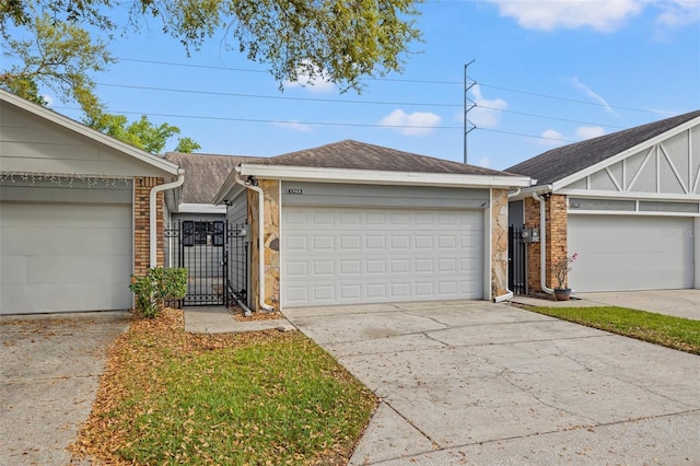 ranch-style home with a gate, driveway, an attached garage, a shingled roof, and brick siding