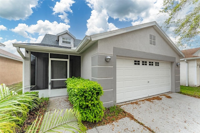 view of front of property with a sunroom, concrete driveway, an attached garage, and stucco siding