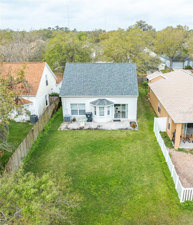 bungalow with a fenced backyard, central AC unit, roof with shingles, and a front yard