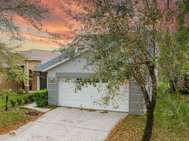 view of front of house featuring a garage, roof with shingles, driveway, and stucco siding