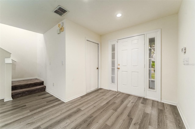 foyer entrance with baseboards, stairs, visible vents, and wood finished floors