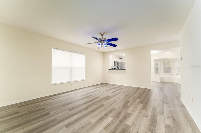 empty room featuring light wood-style floors, ceiling fan, and baseboards