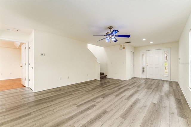 interior space with visible vents, baseboards, ceiling fan, stairway, and light wood-style floors