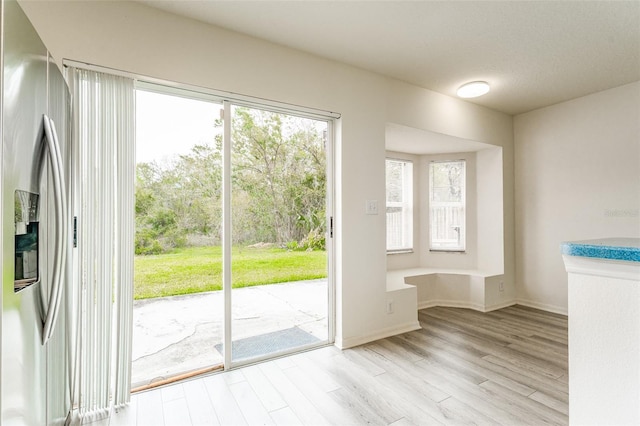 doorway featuring light wood finished floors and baseboards