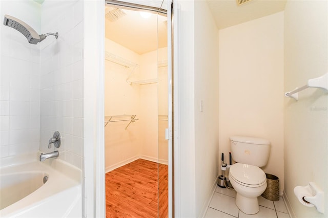 full bath with tile patterned flooring, toilet, shower / bath combination, baseboards, and a walk in closet