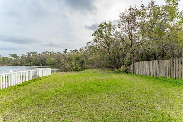 view of yard with a water view and fence