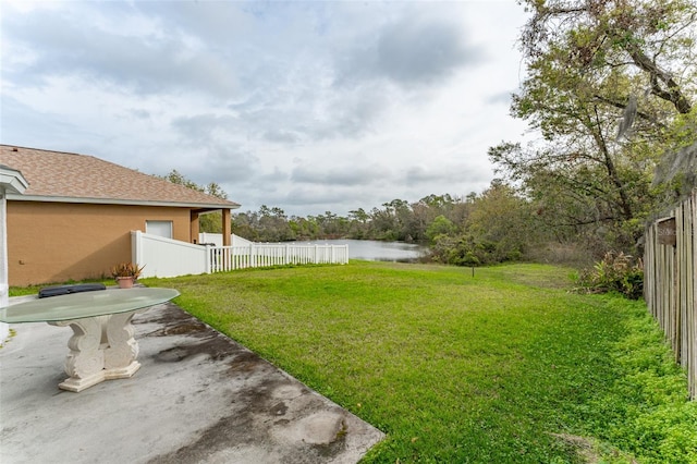 view of yard featuring a water view, fence, and a patio