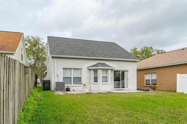 rear view of property with stucco siding, a shingled roof, a patio, and a yard