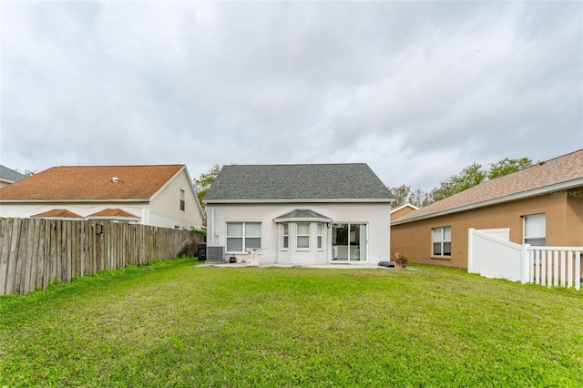 back of property featuring a fenced backyard, a yard, central AC unit, and stucco siding