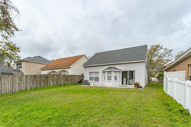 back of property featuring a fenced backyard, roof with shingles, a yard, central air condition unit, and stucco siding