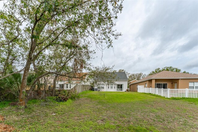 rear view of property with a lawn, fence, and stucco siding