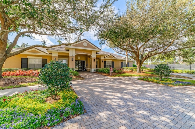 view of front facade with decorative driveway, a tiled roof, and stucco siding