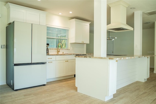 kitchen featuring a sink, visible vents, freestanding refrigerator, light wood finished floors, and island exhaust hood