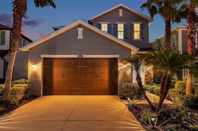 traditional home with concrete driveway, an attached garage, and stucco siding