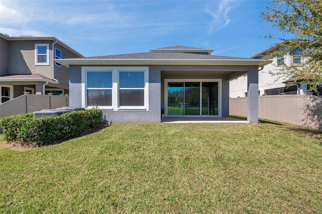 rear view of property with a patio area, fence, a lawn, and stucco siding