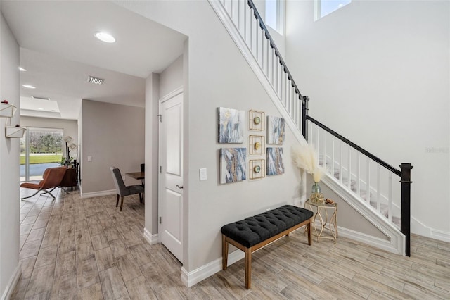 stairs featuring visible vents, a towering ceiling, baseboards, and wood finished floors