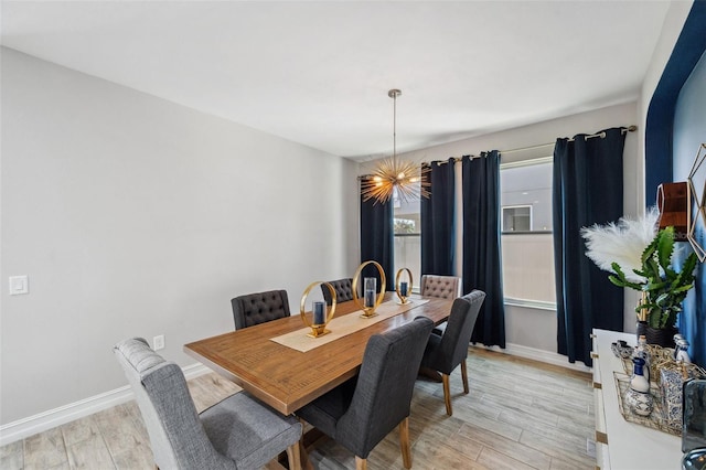 dining space with baseboards, light wood finished floors, and an inviting chandelier