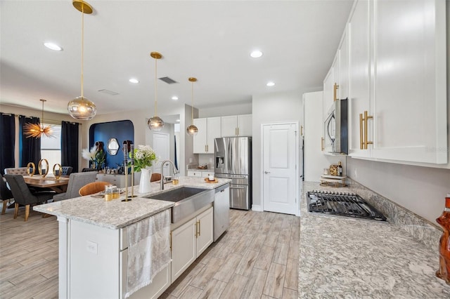 kitchen with appliances with stainless steel finishes, wood finish floors, a sink, and visible vents