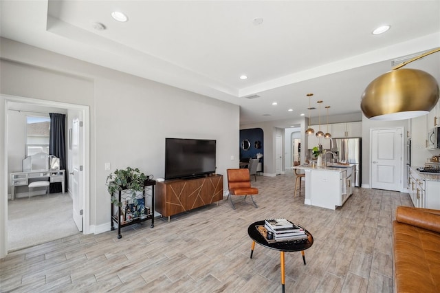 living room featuring wood tiled floor, a tray ceiling, baseboards, and recessed lighting